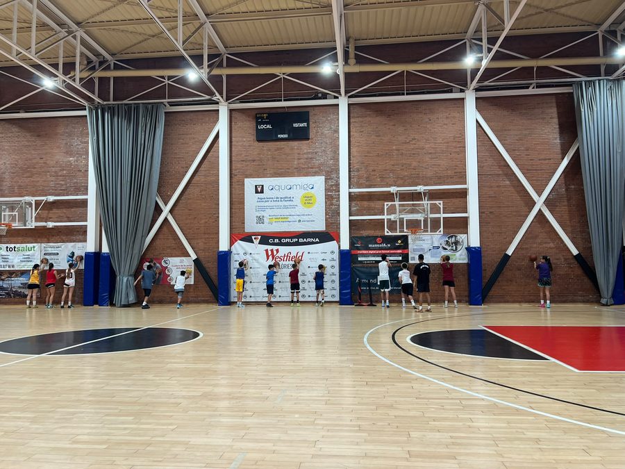 Jugadores y jugadoras del campus de baloncesto del CB Grup Barna tirando a canasta en La Nau del Clot