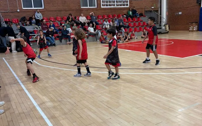 Entrenament de l'Escola de Bàsquet del CB Grup Barna a la pista, amb famílies a la grada